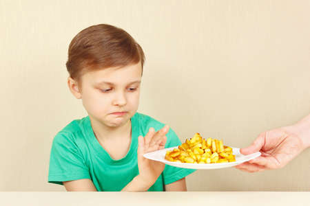 Little cute unhappy boy refuses to eat a french friesの写真素材