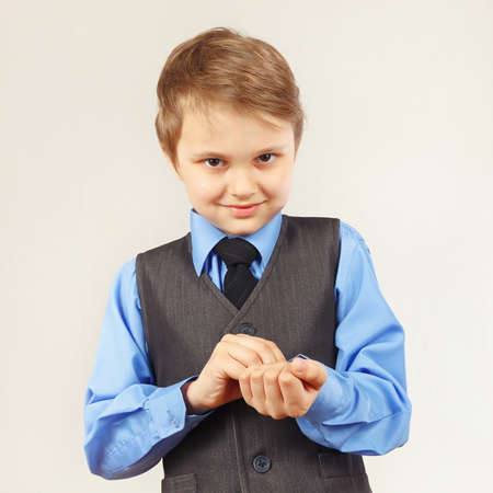 Little stylish gentleman fastened the buttons on sleeve his blue shirtの写真素材