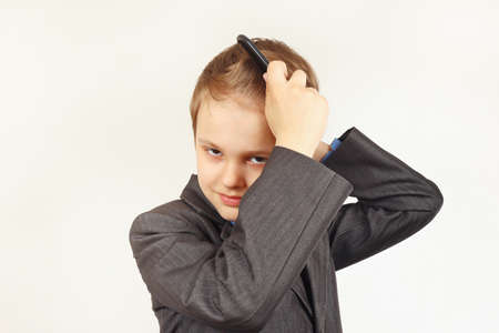 Little stylish boy in a business suit comb a hairbrushの写真素材
