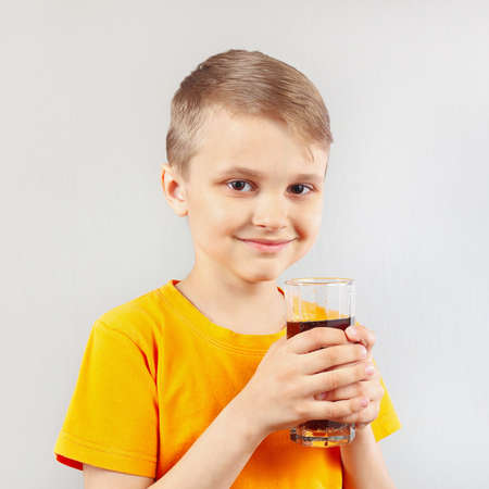 Little blonde boy with a glass of fresh colaの写真素材