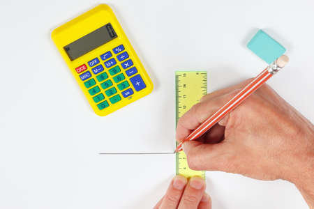 Hands at work with a pencil and ruler on a white sheet of paper