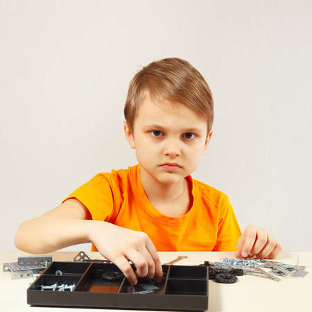 Little boy is going to play with metal constructor at the tableの写真素材