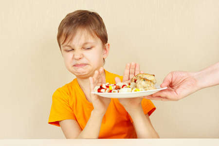 Little discontented boy refuses to eat a pasta with rissoleの写真素材