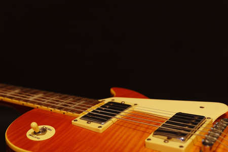 Honey sunburst vintage electric jazz guitar closeup on the black background, with plenty of copy space. Selective focus.の写真素材