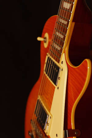 Honey sunburst vintage electric blues guitar closeup on the black background. Shallow depth of...