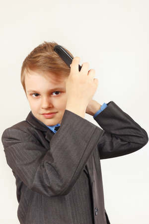 Little gentleman in a elegant suit comb a hairbrushの写真素材