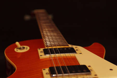 Solid body electric guitar closeup on the black background. Selective focus.