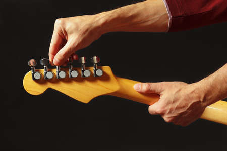 Hands of musician tunes the electric guitar on the black backgroundの写真素材