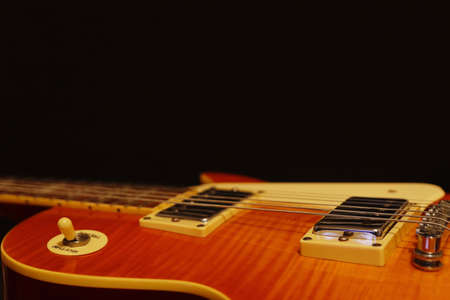 Honey sunburst vintage electric blues guitar closeup on the black background, with plenty of copy...