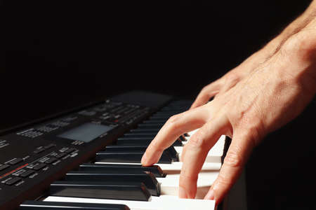 Hands of musician playing the electronic synth on a black background