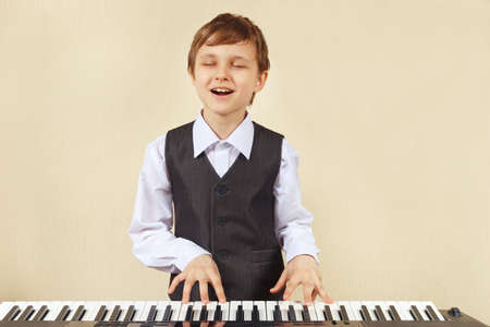 Little cut boy in a suit playing the electronic organの写真素材