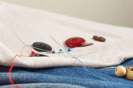 Vintage buttons, pins and needles with threads on canvas and denim close upの写真素材