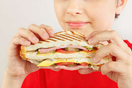 Funny boy in red with a tasty sandwich on a white background close upの写真素材