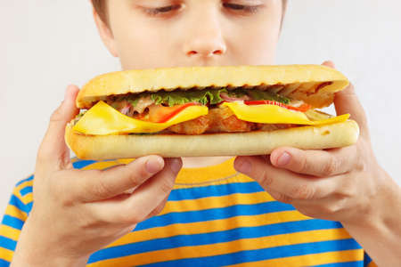Little boy sniffing the tasty cheeseburger on a white background close upの写真素材
