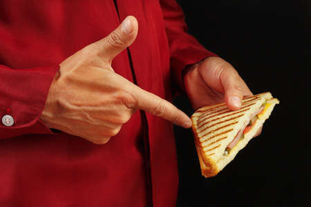 Man in red shirt recommends sandwich on a black background close up