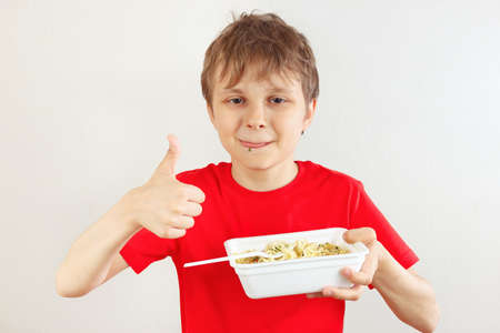 Little funny boy in a red shirt recommends instant noodles on a white background.の写真素材