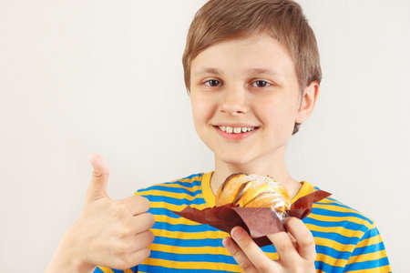 Young boy in a striped shirt recommends sweet apple cake on a white background.の写真素材