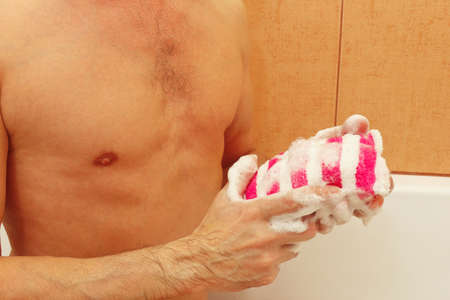 Young man with soaped sponge in the bathroom close up