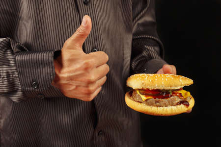 Man in black shirt recommends  and likes big hamburger on a black backgroundの写真素材