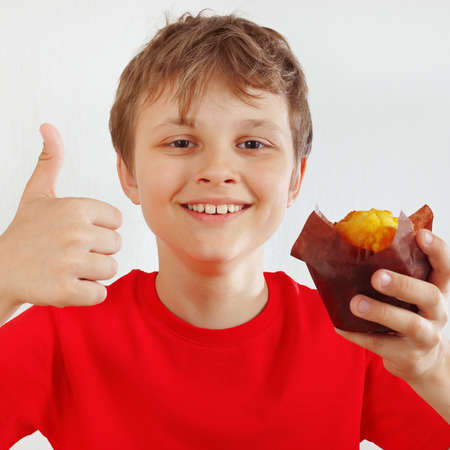 Little funny boy in a red shirt recommends muffin on a white backgroundの写真素材