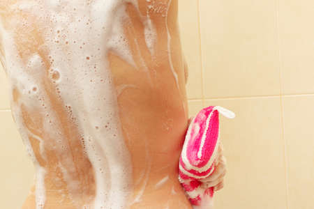 Handsome woman soaps the body in the bathroom close up
