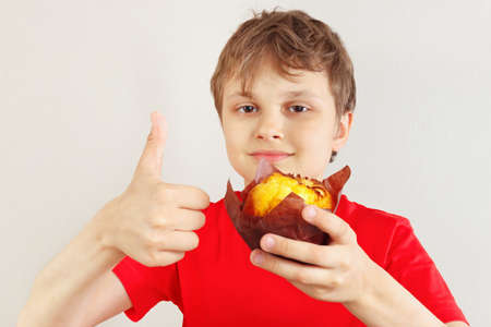 Little funny boy in a red shirt recommends muffin on a white background.の写真素材