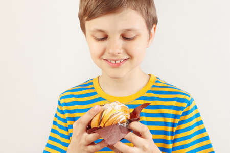 Little funny boy in a striped shirt with apple cake on a white backgroundの写真素材