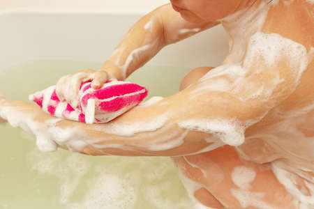 Attractive woman lathering sponge hand in the bathroom close up