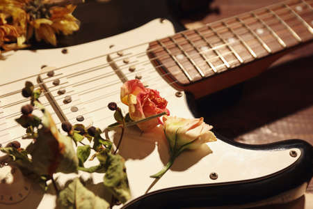Electric guitar, dried flowers and old sheet music on wooden background close up.の写真素材