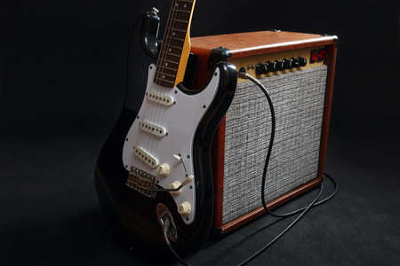 Combo for electric guitar with black guitar on the black background.