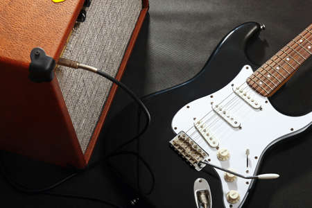 Brown tube combo amplifier for electric guitar with black guitar on the black background.の写真素材