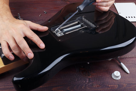 Guitar master adjusts the springs of tremolo bridge on electric guitar.の写真素材