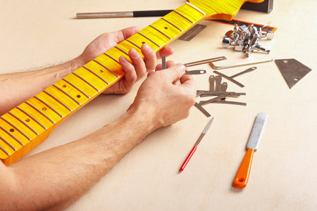 Guitar repairman checks radius of fingerboard of the neck electric guitar.の写真素材