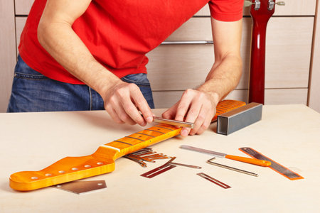 Guitar master crowning frets on the guitar neck with special fret files.の写真素材