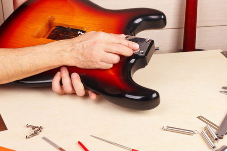Guitar technician sets neck plate on the guitar body.の写真素材