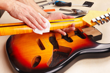 Guitar master polishes the neck of electric guitar.の写真素材