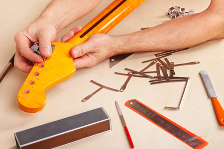 Guitar repairer installs tuners on neck of the electric guitar.の写真素材