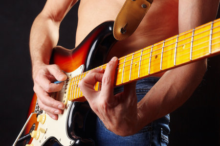 Artist playing the sunburst electric guitar on a dark stage.の写真素材