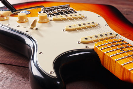 Solid body electric guitar closeup on the wooden background. Selective focus.の写真素材