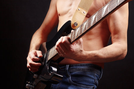 Rock guitarist playing chord on guitar on a dark stage.の写真素材