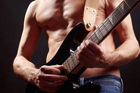 Rock musician playing solo on guitar on a dark stage.の写真素材