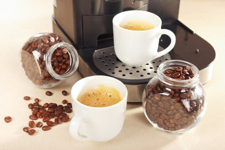 Cups of espresso and cans of coffee beans on the light table.の写真素材