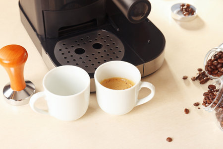 White cups of espresso, tamper and cans of coffee beans on the kitchen table.の写真素材