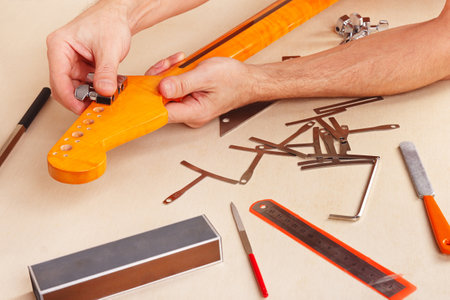 Guitar technician installs tuners on neck of the electric guitar.の写真素材
