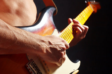 Rock musician playing the sunburst guitar on a dark stage.の写真素材