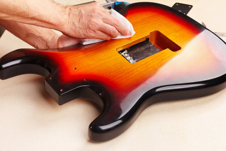 Guitar repairer polishes the body of electric guitar.の写真素材