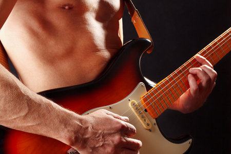Rock musician playing the sunburst electric guitar on a dark stage.の写真素材