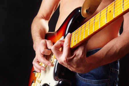 Guitarist playing the sunburst guitar on a dark stage.の写真素材