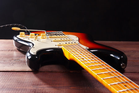 Solid body electric rock guitar closeup on the wooden background. Selective focus.の写真素材