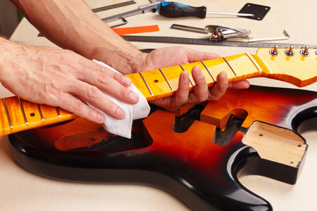 Guitar technician polishes the neck of electric guitar.の写真素材